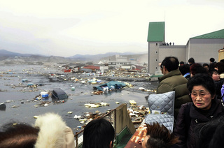 津波に破壊される街を見る人たち